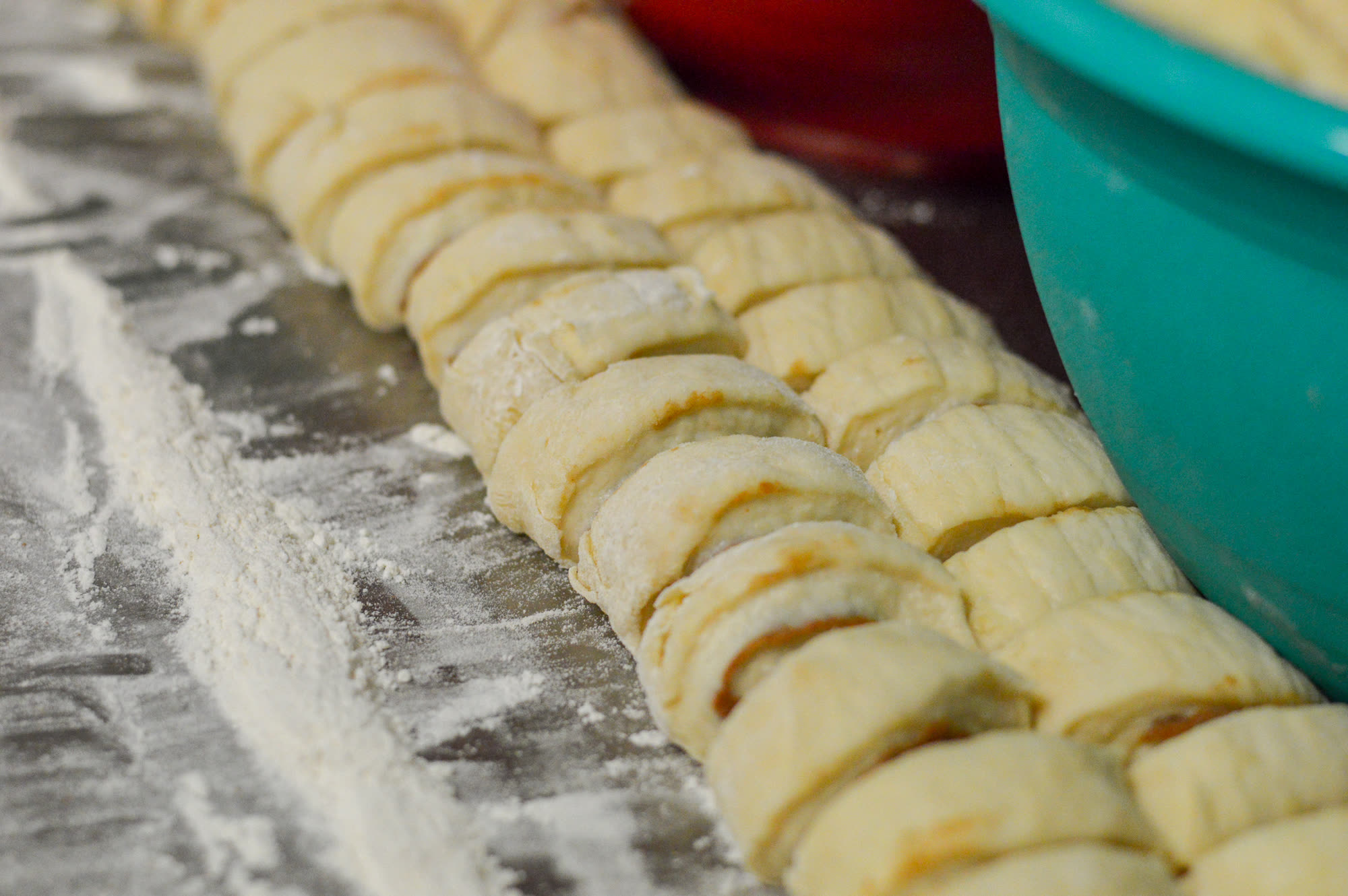Hand-cut cinnamon roll dough on a floured board